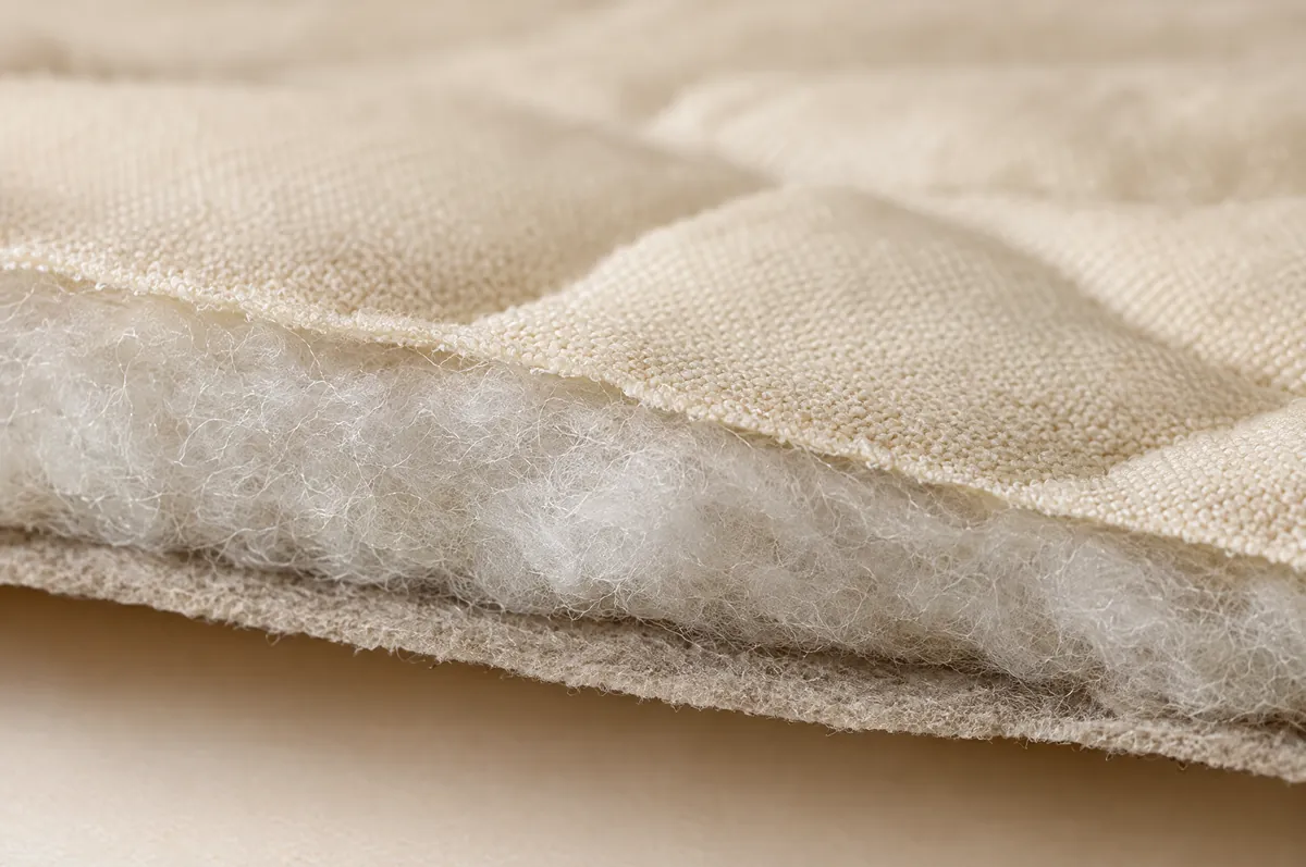 Průřez prošívaného materiálu: vrchní látka, rouno a netkaná textilie
